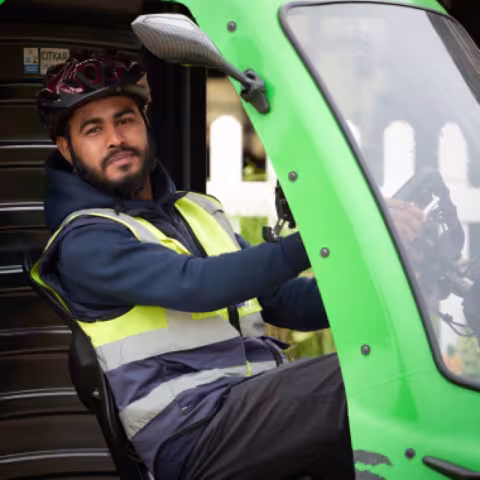 A cycle courier in hi-vis seated in a delivery vehicle