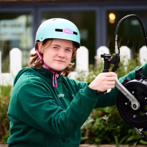 A young cyclist in a helmet getting their bike ready to ride.